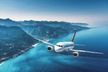 aircraft-is-flying-islands-sea-sunrise-summer-landscape-with-white-passenger-airplane